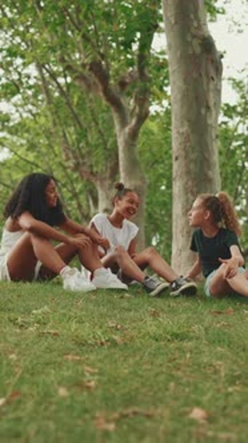 Three girls sit on the grass in the park and emotionally talking