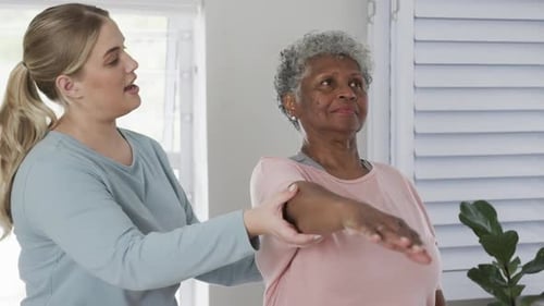 Young Woman Helping Senior Woman Exercise Arm