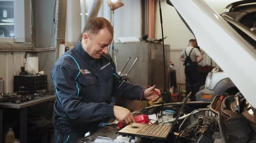 Professional Mechanic Doing a Car Inspection He is Testing a Car Battery with a