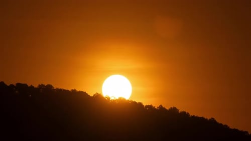 Timelapse of dramatic sunrise with orange sky in a sunny day.