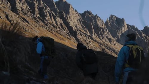 Group trekking uphill Norwegian mountains during sunny day,slow motion tracking shot