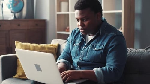 Man Typing on Laptop Computer on Couch