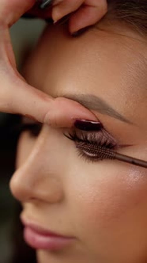 Makeup Artist Applying Brown Mascara on Model's Long Eyelashes During Professional Beauty Treatment