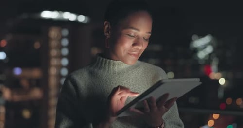Woman Smiling Using Tablet at Night in City