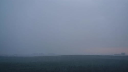 Stormy sky at sunset with dark rain clouds. Rain over a summer forest with green trees