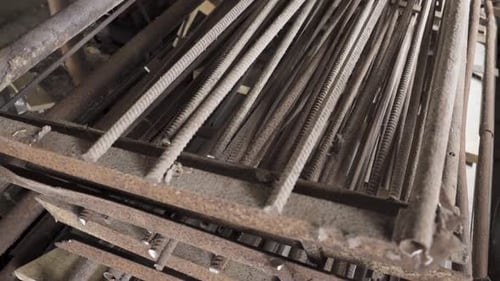 panning shot of rusty steel reinforcement rebar in storage, close up