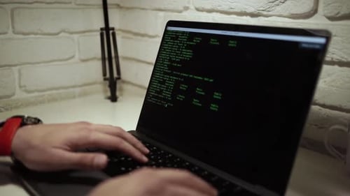 Hands Typing on Laptop With Green Computer Code