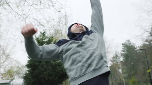 Man Jogging in Park Reaches Arms Upward