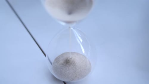 Sand Runs Through Hourglass Timer on White Surface