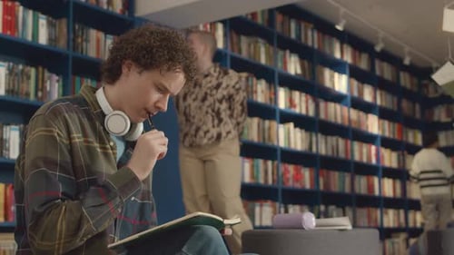Curly Male Student Working on Essay in Public Library