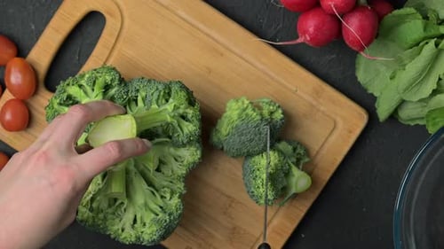 Cutting Fresh Broccoli on Cutting Board for Meal