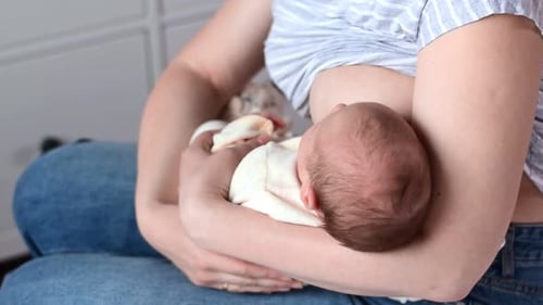 Woman Breastfeeding Newborn Baby at Home
