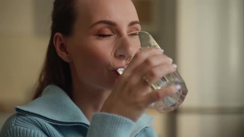 Closeup of a Woman Drinking Water From a Glass in the Living Room The Concept of a Healthy Lifestyle