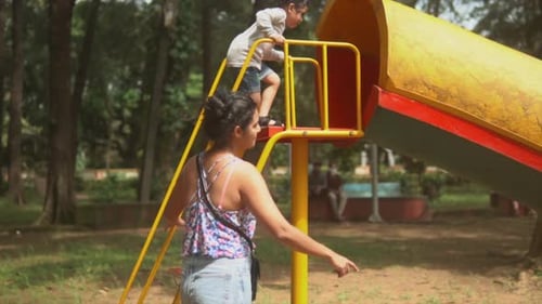Brunette woman playing with a child in a playground in slow motion.