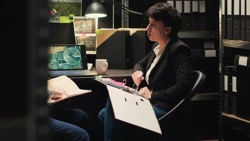 Detectives Reviewing Evidence at Desk at Night