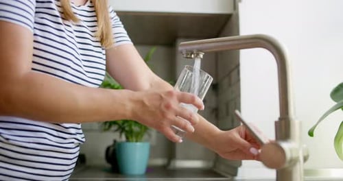 Woman Filling Glass with Water from Faucet