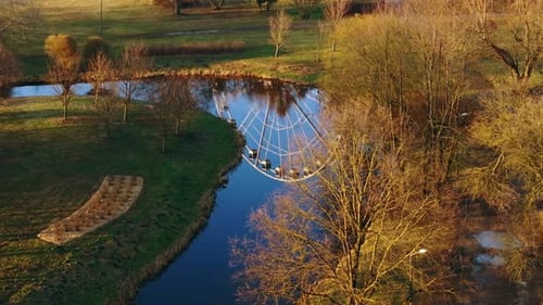 Golden Ferris Wheel Reflection in Tranquil Water at Uzvaras Park Riga at Spring