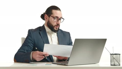 Dedicated Businessman Reviewing Documents Intently on Laptop in Office