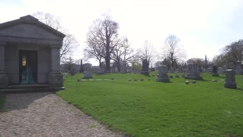 SLOW MOTION (48FPS): Driving slowly by an old mausoleum and rows of old headstones through a cemeter