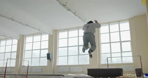 Mann springt auf ein Trampolin, um an Höhe zu gewinnen, bevor er einen Salto über eine Kiste in einem