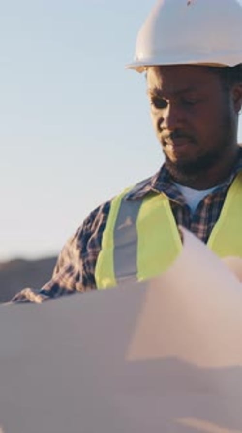 Professional Builder Examining Drawings and Blueprints in Construction Site Portrait of Architect
