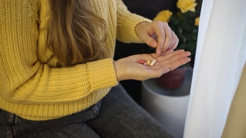 Woman holds pills and vitamins in her hand