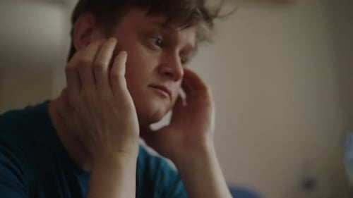 Gros plan d'un jeune homme en détresse assis seul dans une pièce, la tête dans les mains, se sentant anxieux et