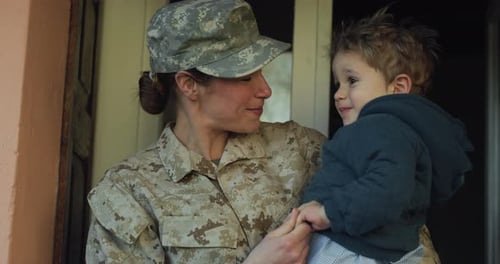 Military Woman Holds and Hugs Child at Home