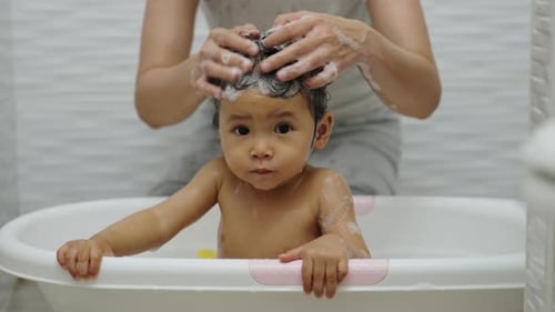Parent Washes Hair of Toddler in Bathtub