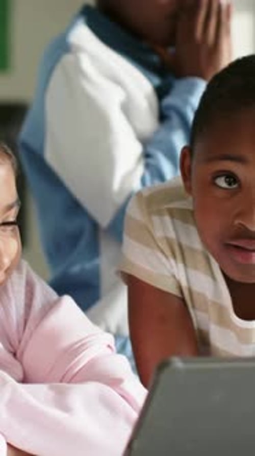 Girl in pink tapping tablet, boy in striped watching, animated icons celebrating classroom lesson