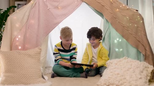 Boys Using Tablet Inside Blanket Fort in Home