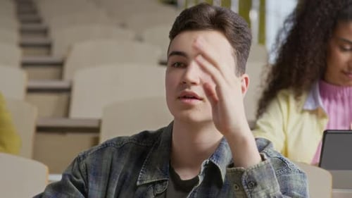 Young Guy Giving Answer during Lecture with Peers in College Auditorium