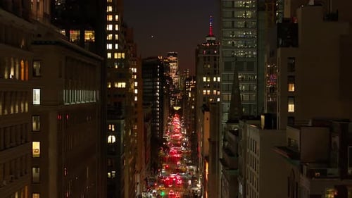 Cars Navigate a Lively Lower Manhattan New York City Street at Night Highlighting Luxury Buildings