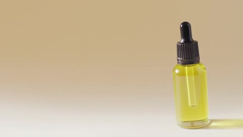 Close up of dropper serum bottle on beige background with copy space