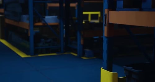 Warehouse Interior with Bright Blue Flooring and Shelves in Dark Lighting