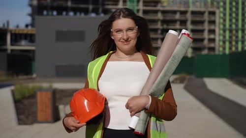 A Professional Woman Working on a Construction Site While Holding Blueprints in Hand