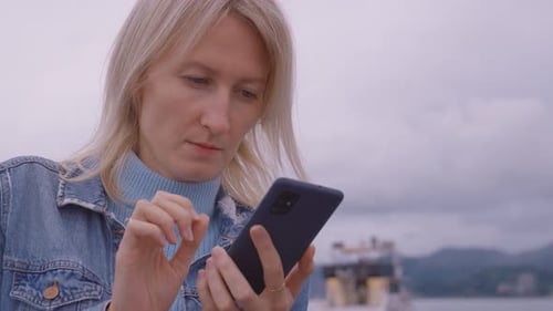 Woman Uses Smartphone Outdoors on Overcast Day