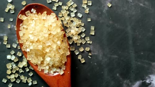 Brown Sugar Cubes in a Spoon on Dark Surface