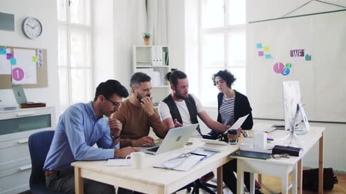 Group of Young Businesspeople with Laptop Working Together in a Modern Office