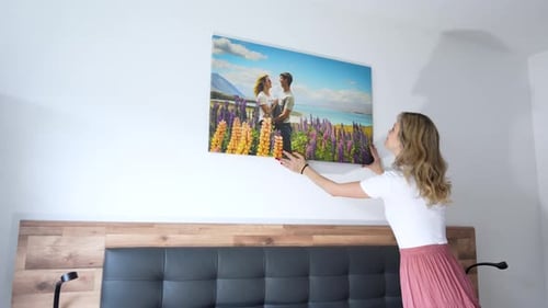 Woman Hanging a Picture in Bedroom