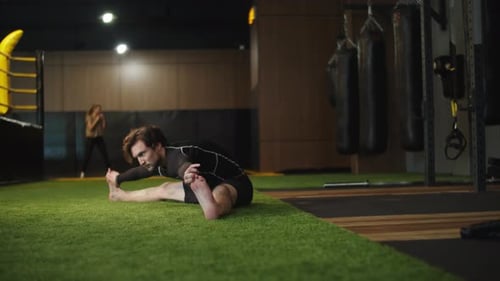 Ehrgeiziger Fitnessmann wärmt sich im Fitnessstudio beim Training im Sportclub mit Split auf