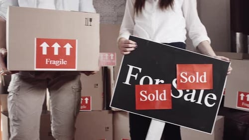 Couple with Moving Boxes and Sold Real Estate Sign
