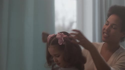 Woman brushing child's hair at home