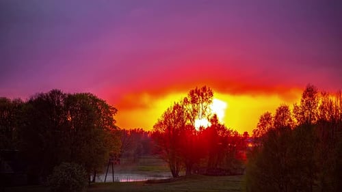Eine atemberaubende Aufnahme eines Sonnenuntergangs über einem See. Schwere Wolken werden bei Sonnenuntergang von der Sonne beleuchtet. Ein Tipp