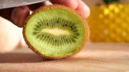 Eine reife Kiwi in Scheiben schneiden, um ihr leuchtend grünes Inneres zum Vorschein zu bringen