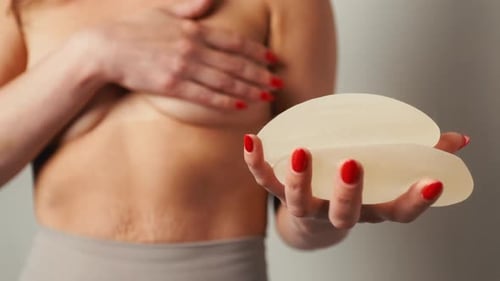 Woman Holds Breast Implants Before Surgery