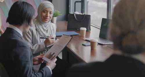 Business Partners Middle Eastern Woman in Hijab and Asian Man Sharing Ideas Discussing Project and