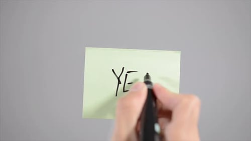 Hand Writes "YES!" on Light Green Sticky Note
