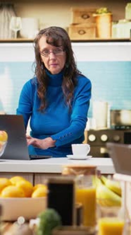 Vertical Video Senior Adult Browsing Internet on Smartphone in Kitchen
