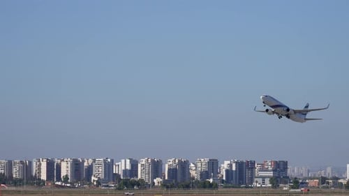 Commercial Airplane Ascending into Blue Sky over Urban City Skyline